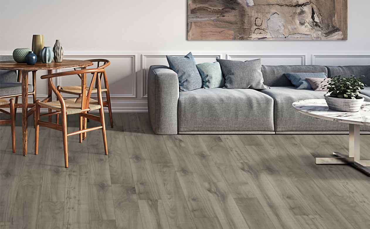 gray wood look flooring in living area with gray sofa and round table with wood chairs