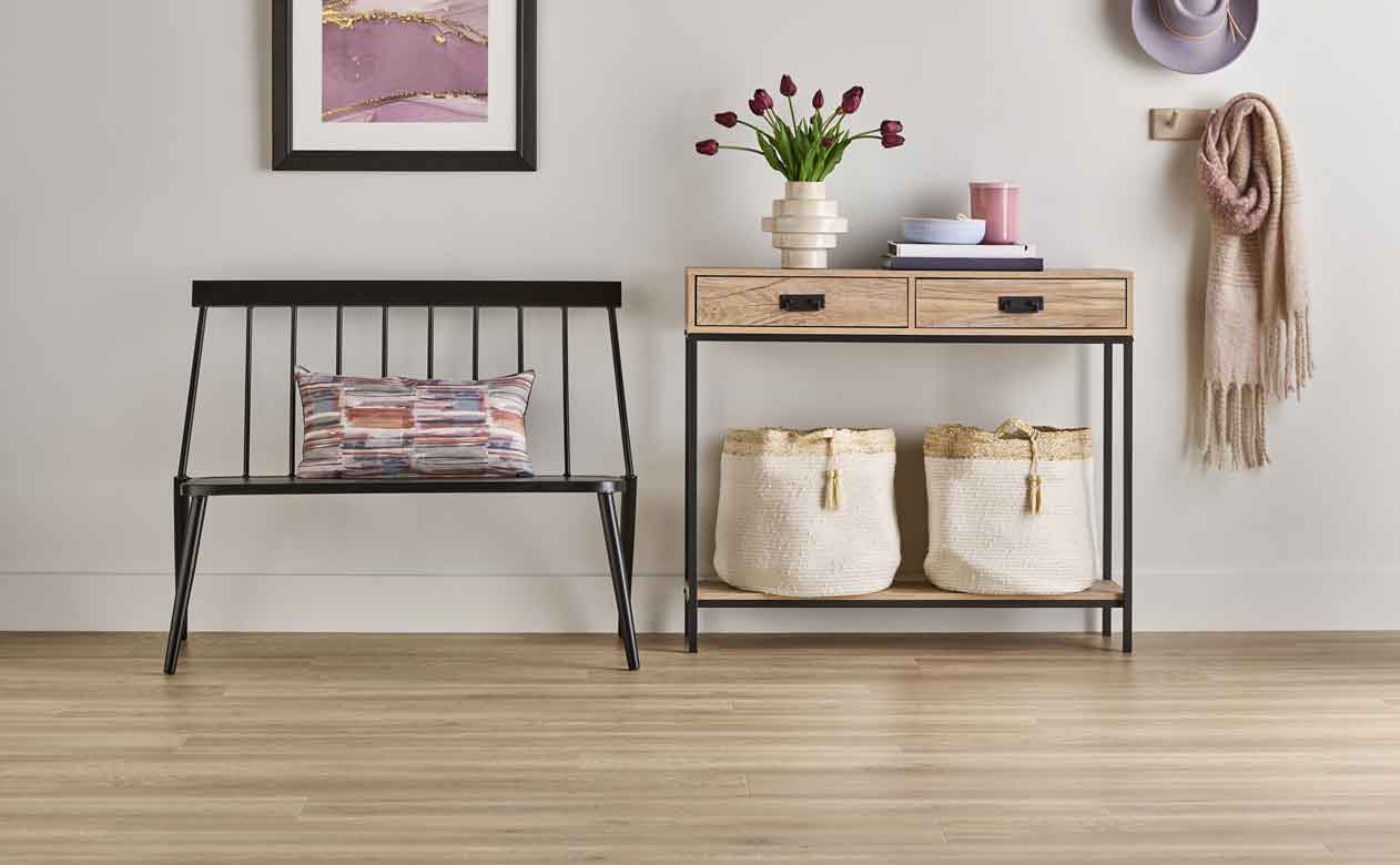 light wood-look laminate flooring in entryway with black bench