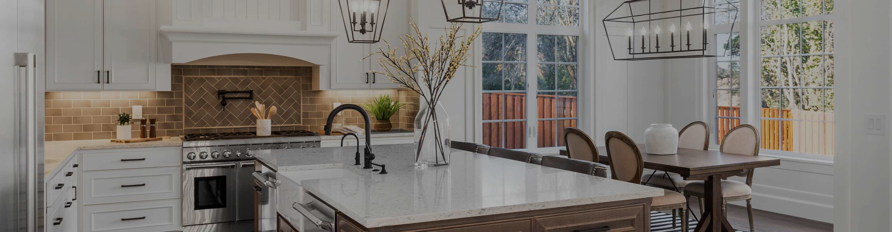 Modern kitchen with white cabinetry, arched pantry backsplash wall , central island in dark wood with marble countertop, stainless appliances, pendant lantern lights, and a window with outdoor view.
