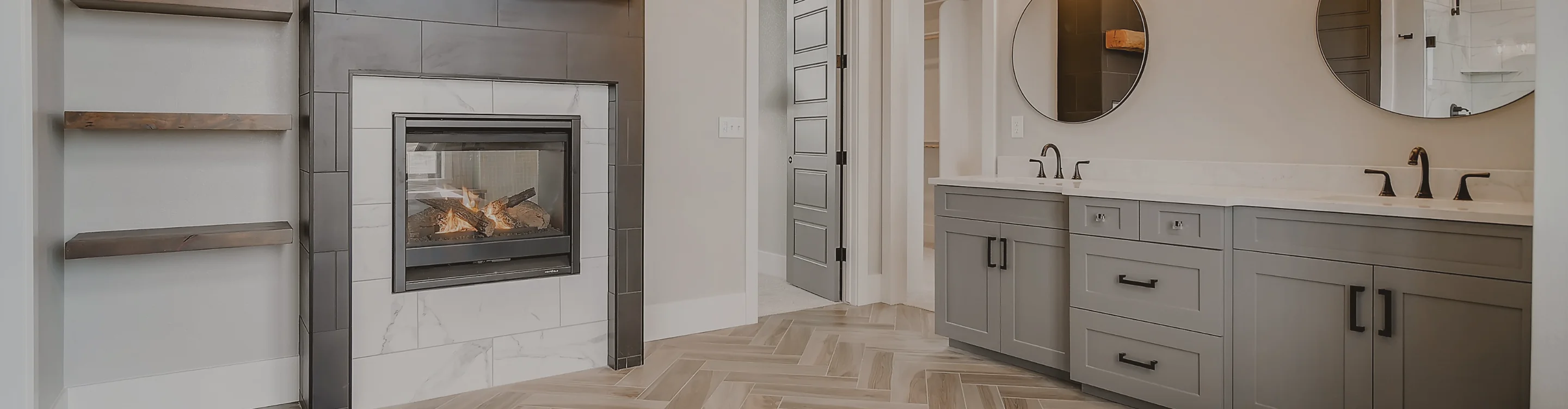 Herringbone flooring with custom vanities and tiled fireplace in a bathroom